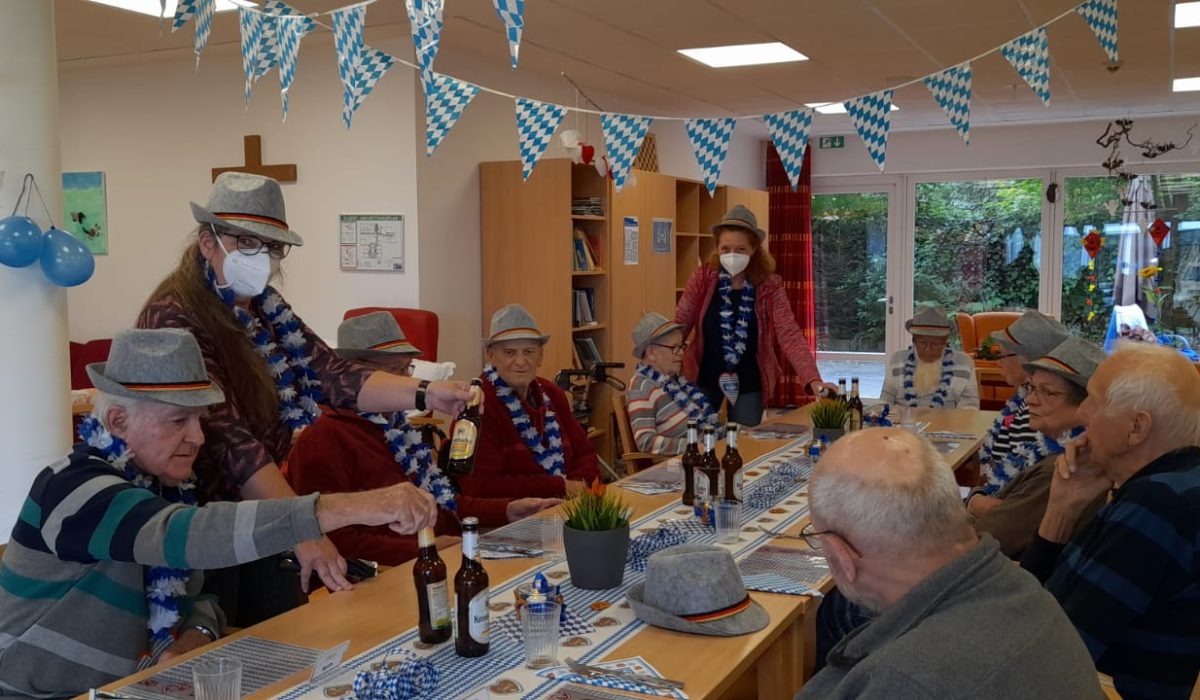 Gäste der Tagespflege sitzen am Tisch verkleidet mit bayrischen Hüten.
