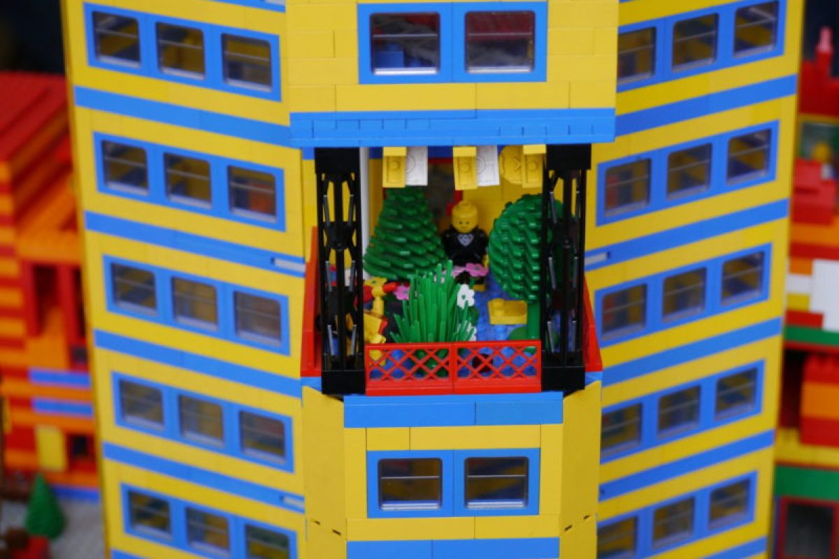 Ein Legomännchen steht auf dem Balkon eines Legohauses.